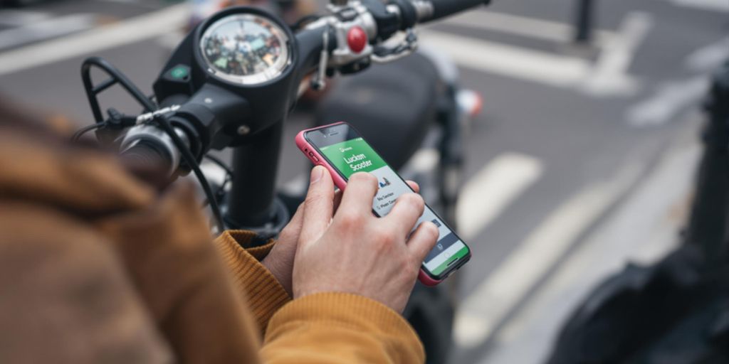 Person nutzt Scooter-App auf Smartphone.